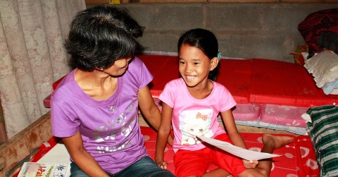 Young girl in the Philippines reads a letter from her sponsor 
