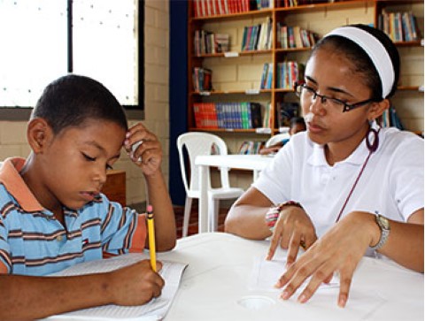 A young boy works on an assignment at a Children International community center library in Colombia.