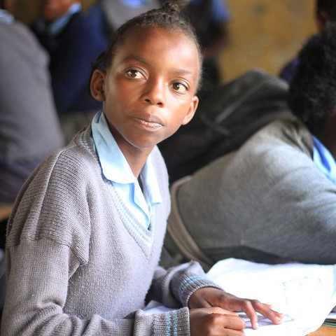 una niña sentada en un escritorio en un salón de clases