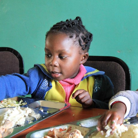 una niña sentada en una mesa comiendo