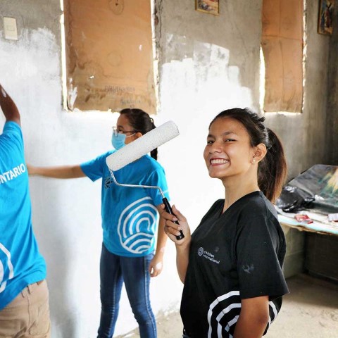 un grupo de personas pintando una pared con un rodillo de pintura