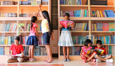 a group of children standing in front of a bookshelf