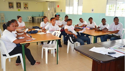 a group of teens sitting at tables in a room