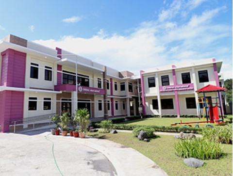 un edificio rosa y blanco con un parque infantil frente a él