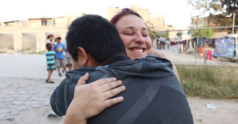 a woman hugging a young boy