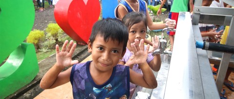 a group of children ready to wash their hands standing next to each other