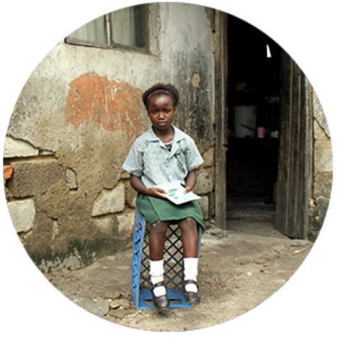 a little girl sitting on a crate reading a book