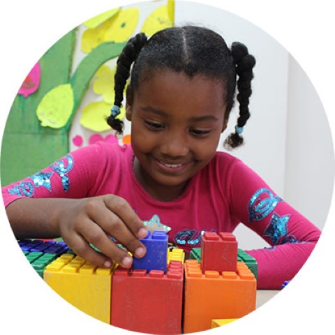 a young girl playing with blocks in a classroom