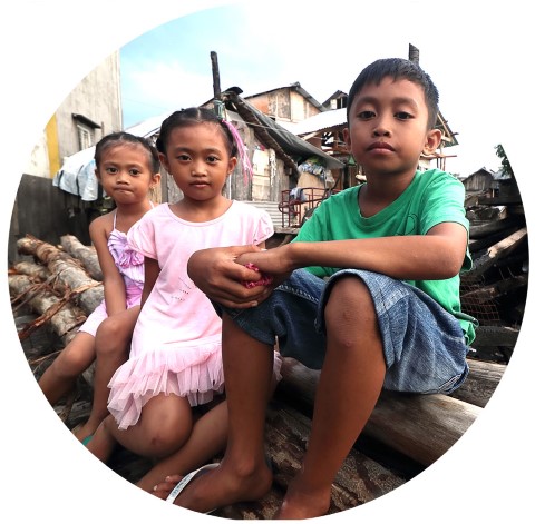un grupo de niños sentados encima de un montón de madera