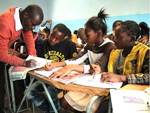 un grupo de niños sentados en escritorios en un salón de clases