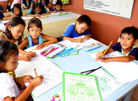 Niños en un centro comunitario colorean un libro sobre la nutrición