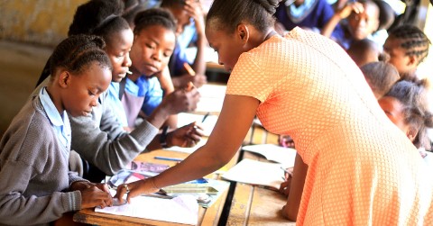 a woman in an orange dress helping a student