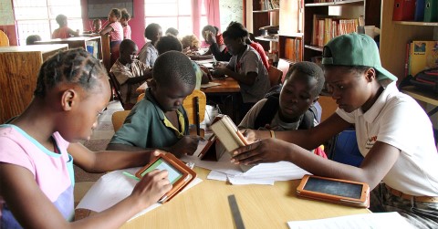 a group of children sitting at a table with books