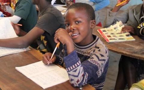 a young boy sitting at a desk with a pencil in his hand