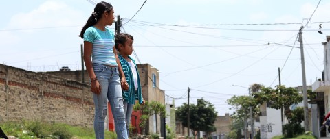 two young girls stand on the street of their neighborhood