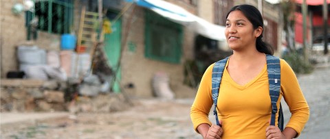 una mujer con una camisa amarilla camina por la calle