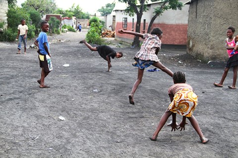 Poor children in Africa play ball in the dirty streets of their community