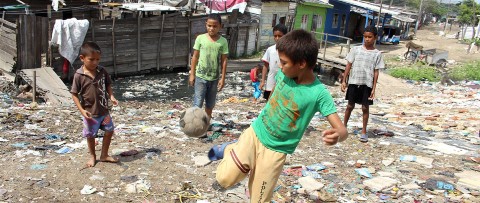 un grupo de niños jugando al fútbol en una calle sucia