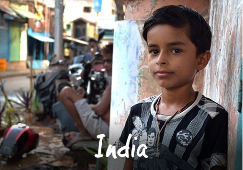 India | a young boy standing in front of a building