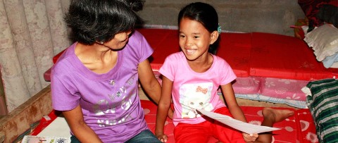 Young girl in the Philippines reads a letter from her sponsor 