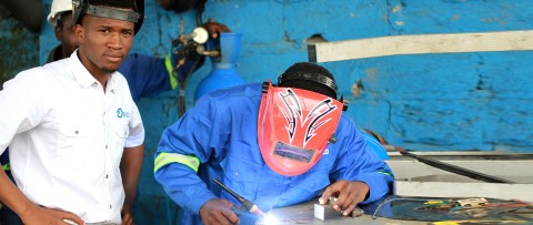 a man in a welding mask and a man in a white shirt