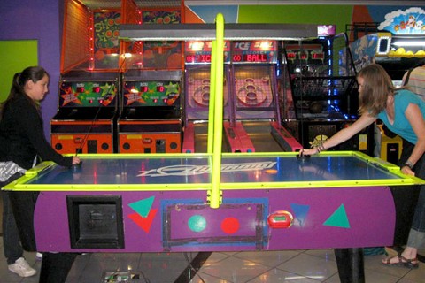 Bernardita and Shalynn play air hockey at an arcade 