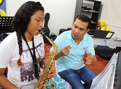An instructor helps a student learn to play the saxophone