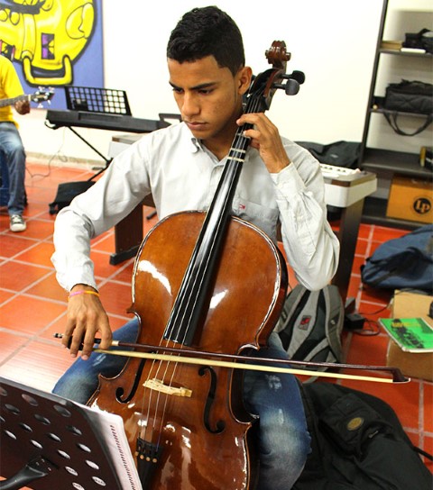 A young man practices the cello.