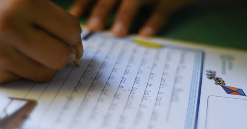 a person writing on a piece of paper with a pencil