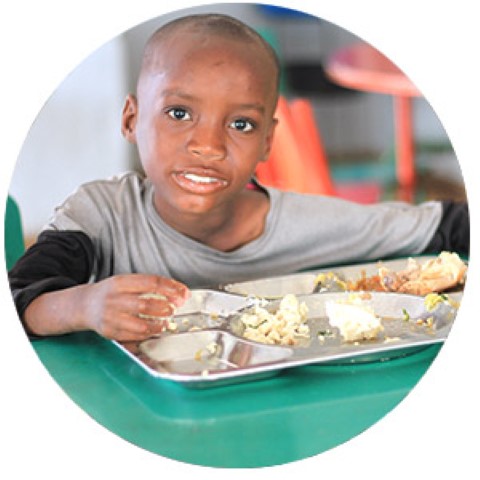 un niño sentado en una mesa con una bandeja de comida