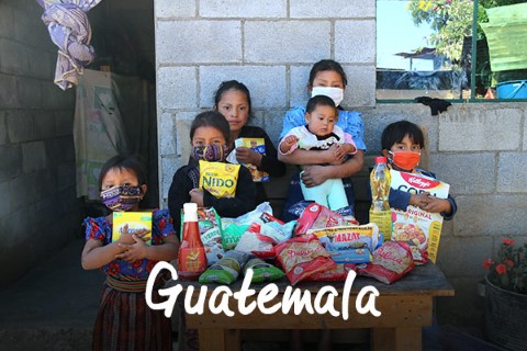 Guatemala | a group of children standing in front of a table full of food