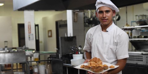 a chef holding a plate of food in a kitchen