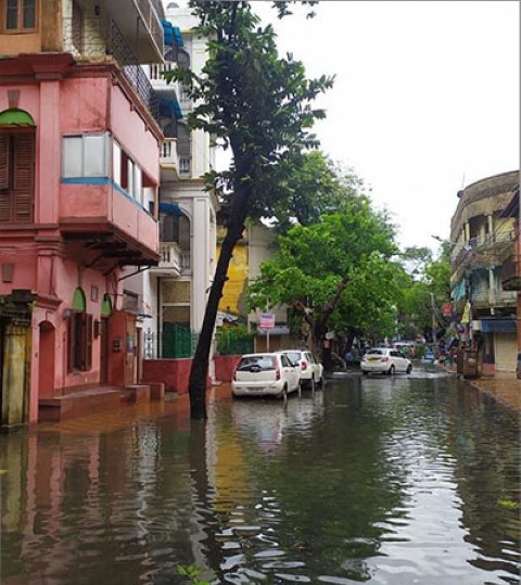 a flooded street with cars parked on the side of it