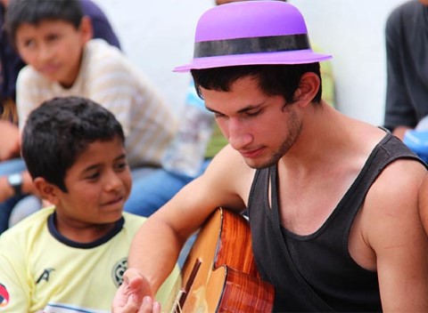 Un joven toca la guitarra para niños en un evento juvenil en México