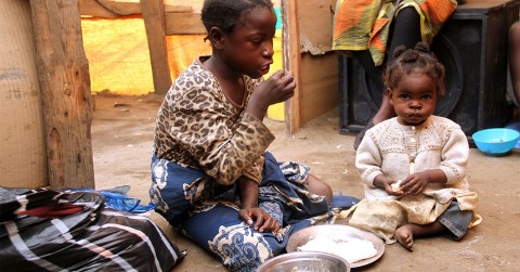 two young girls sitting on the floor eating