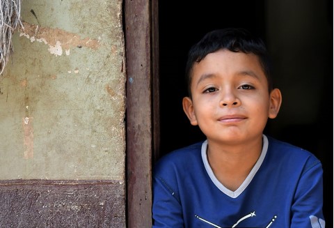 a young boy sitting in the doorway of a building | un niño sentado en la puerta de un edificio