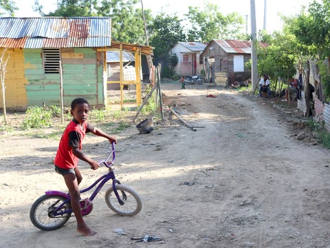 a young boy riding a bike down a dirt road