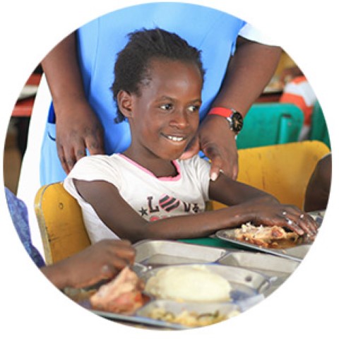 a little girl sitting at a table with a plate of food