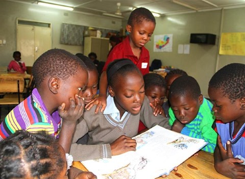Una joven lee un libro a los niños en un centro comunitario de Lusaka