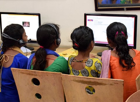 Four girls share a computer screen as they work together on an assignment