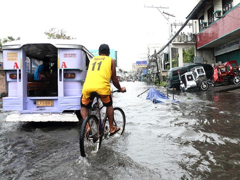 Los filipinos como este hombre en bicicleta son expertos para transportarse durante las inundaciones.