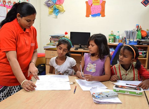 Un tutor de Children International ayuda a tres estudiantes con sus tareas