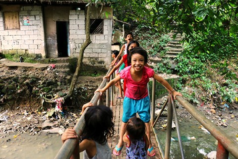 Kids in poverty play on a bridge over polluted water