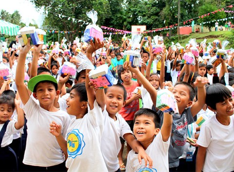 Kids hold up hygiene kits.