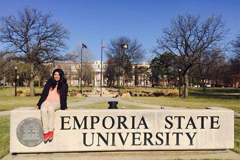 Johanny sentada en un banco en el campus de Emporia State University