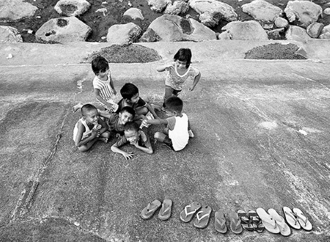 Siete niños juegan descalzos en el malecón inclinado a 45 grados.