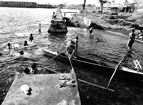 Un pescador navega por nadadores para atracar su lancha.