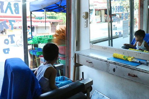 Christian watches passersby on a busy street in Manila, Philippines. 