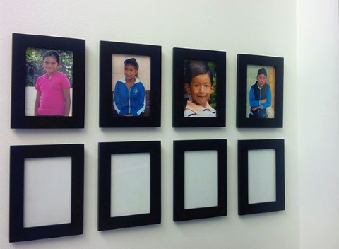 Photos of sponsored children hang in the Delos Advisors office 