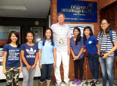 Chris Kent poses in front of a CI community center in the Philippines with six of his sponsored kids.